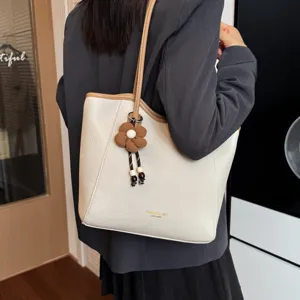 Detailansicht der beigen Freizeit-Tasche mit elegantem Blumenanhänger und Leder-Besatz.