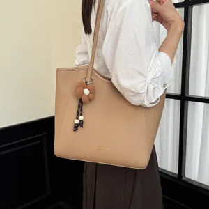 Detailansicht der beigen Leder-Shopper-Tasche mit Blumenanhänger und bequemem Schulterriemen.
