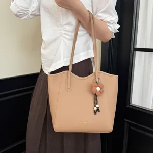 Detailansicht der beigen eleganten Leder Tote Umhängetasche mit stilvollem Blumen Taschenanhänger.