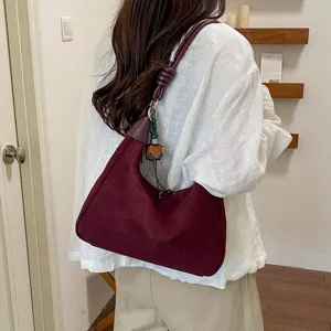 Vue de détail montrant un sac à épaule souple en suédine bordeaux avec nœud de sangle.