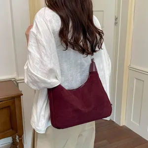 Vue détaillée du sac porté épaule en daim bordeaux, présentant une texture douce et élégante.