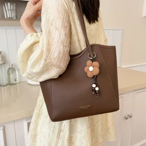 Braune Damentasche mit grossem Fassungsvermögen, elegante Schultertasche mit Blumenanhänger.