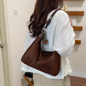 Vue détaillée du sac porté épaule en suédine marron par le modèle, style vintage d'automne.