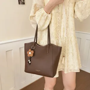 Braune Leder Tote Bag Detailansicht mit robusten doppelten Trägern und süßem Blumenanhänger.