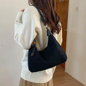 Vue détaillée du sac porté épaule hobo en suédine noire avec bandoulière nouée élégante.