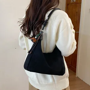 Vue détaillée d'un sac porté épaule élégant en suédine noire, design minimaliste et chic.