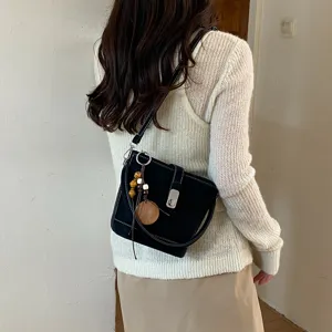 Vue détaillée d'un sac seau noir élégant avec coutures contrastées et breloques en bois.