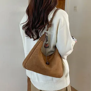Détail de sac porté épaule hobo en suédine marron, sac bandoulière vintage mode automne.