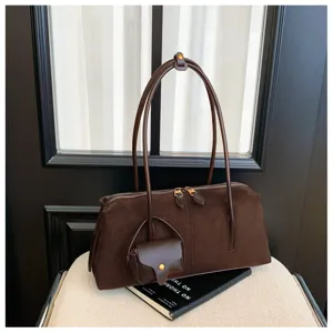 Dark brown suede shoulder bag with long handles and a mini pouch charm, retro detail.