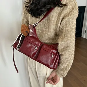Wine red shoulder bag with dual front pockets, cute bear pendant and stylish striped scarf.