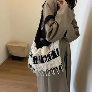 Close-up detail of black and white knit fringe shoulder bag, spacious casual resort style.