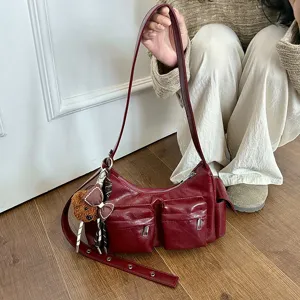 Detailed view of women red shoulder bag with multi pockets and cute bear pendant charm accessory.
