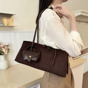 Brown suede underarm shoulder bag detail showing texture and attached mini pouch charm style.