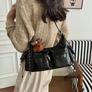 Black leather shoulder bag with multiple front zip pockets and cute bear charm for women.