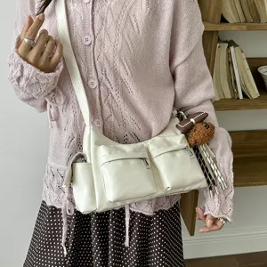 Detailed view of white PU leather multi-pocket crossbody bag with cute plush puppy charm.