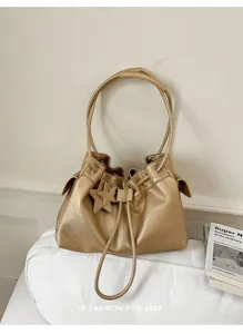 Gedetailleerd uitzicht van de metallics gouden emmeltas met sterrenhanger en trekkoord.