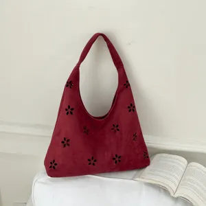 Dettaglio borsa hobo in camoscio rosso, elegante motivo floreale traforato su borsa.
