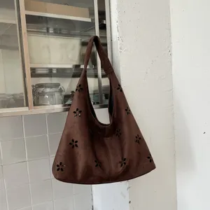 Dettaglio borsa hobo in camoscio marrone, con eleganti motivi floreali intagliati e ampio spazio.