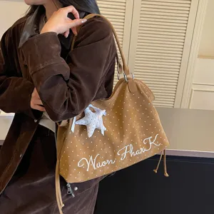 Close-up view of the brown polka dot tote bag with a star charm and embroidered letters detail.