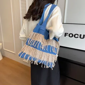 Detail view of stylish blue knitted fringe shoulder bag in casual lifestyle indoor setting.