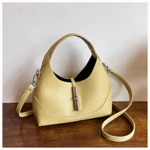 Detail view of a stylish yellow leather hobo shoulder bag with classic metal lock closure.