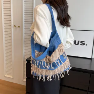 Blue knitted shoulder bag detail showcasing textured weave and decorative fringe tassels.