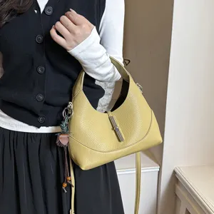Detailed shot of a stylish yellow leather hobo shoulder bag with metal lock closure.