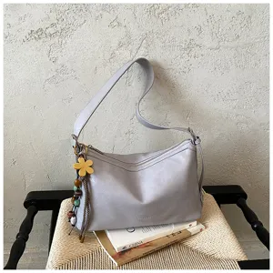 Detail view of stylish grey hobo shoulder bag with charming flower pendant for commute.