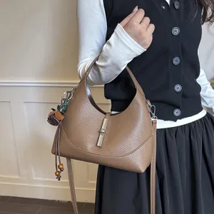 Detailed close-up of brown leather hobo shoulder bag featuring stylish metal lock and cute charm.