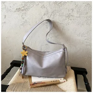 Chic grey leather shoulder bag detail with floral pendant and zipper for daily commute.