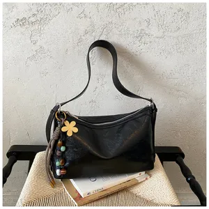 Close-up detail of the black leather shoulder bag showcasing its unique flower charm and strap.