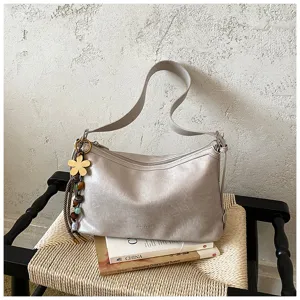 Detail view of a light gray shoulder bag featuring a chic flower charm and textured PU leather finish.