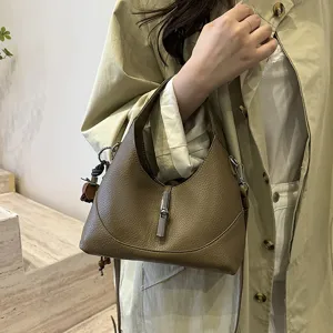Detailed close-up shot of a brown textured leather hobo shoulder bag featuring a stylish metal bamboo clasp.