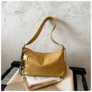 Detailed view of stylish yellow hobo shoulder bag with flower charm on rustic woven chair.