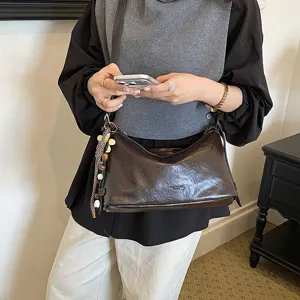Brown soft leather shoulder bag with chic hanging charms for women daily commute style.