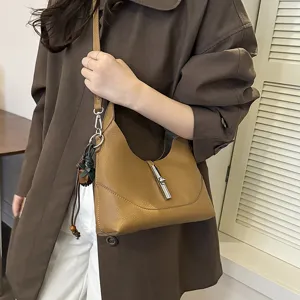 Detail view of a stylish brown leather hobo shoulder bag with classic metal lock design.