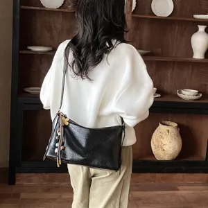 Stylish black leather shoulder bag with chic charms, large capacity commuting messenger design.