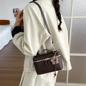 Primo piano della borsa a tracolla intrecciata marrone, che mostra la sua texture elegante.