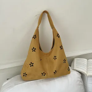 Vista dettagliata della borsa hobo in camoscio senape con intagli floreali e ampio spazio interno.