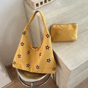 Borsa a spalla in camoscio giallo con motivo floreale ritagliato e pochette coordinata.