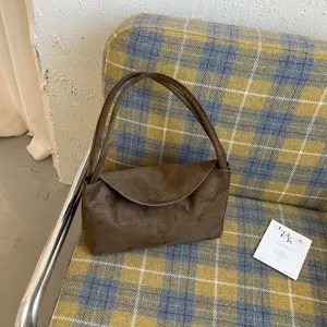 Détail de sac à bandoulière en suédine marron, texture chic et design de rabat minimaliste.