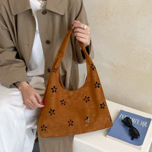 Primo piano della borsa hobo in camoscio marrone con motivi floreali traforati e grande capienza.