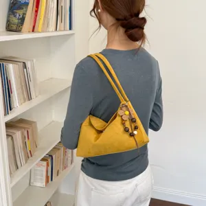 Gelbe Wildleder Schultertasche Detailansicht, schicke Beuteltasche mit Blumen Anhänger.