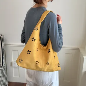 Vista dettagliata della borsa a spalla hobo in camoscio giallo da donna con intagli a fiore.