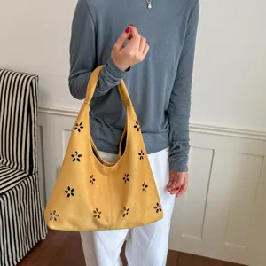 Dettaglio borsa a spalla hobo gialla con motivi di fiori ritagliati e morbido materiale scamosciato.