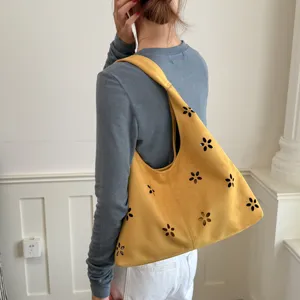 Vista ravvicinata della borsa a spalla gialla hobo con intagli floreali e morbido camoscio.