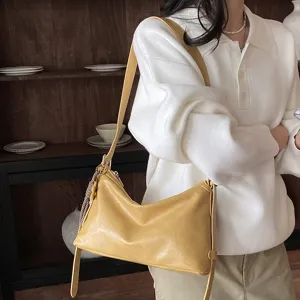 Detail view of the stylish yellow hobo shoulder bag worn by model in cozy indoor setting setup.