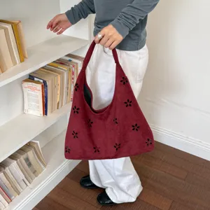Vista dettagliata della borsa a spalla hobo in camoscio rosso vino con motivo floreale intagliato.