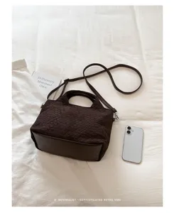 Vista detallada del elegante bolso tote marron oscuro tejido con textura y base solida.