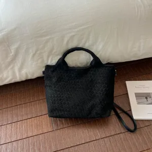 Vista detallada del bolso tote negro con textura tejida, bolso de hombro casual diario.